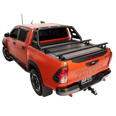 Rear three quarter view of orange Toyota Hilux Rugged X with HSP Load Bars fitted over closed HSP Roller Cover