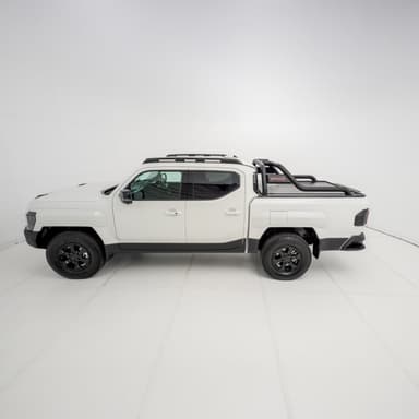 Three-quarter side view of a white Kia Tasman with the HSP Roll R electric roller cover installed, highlighting the closed roller shutter and curved black sports bars positioned over the tub.