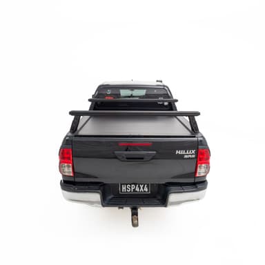 HSP Load Rack JNR fitted to black Toyota Hilux dual cab, straight rear view showing low profile rack over closed HSP Roller Cover